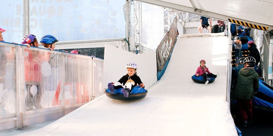 Children tobogganing down a fake ice hill 